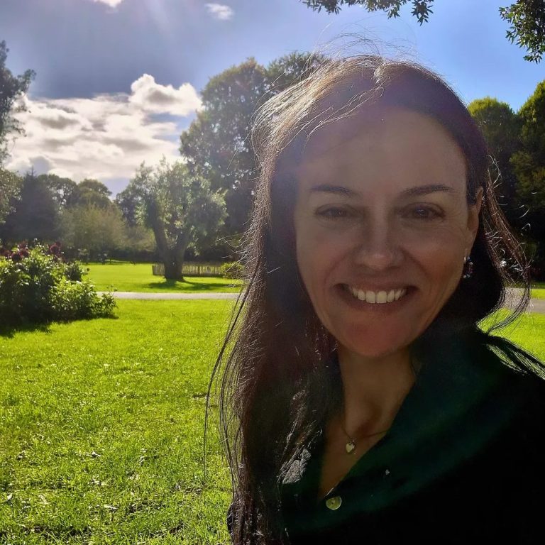 Conciencia de corazón Mujer sonriente en un parque con césped y árboles bajo un cielo despejado.